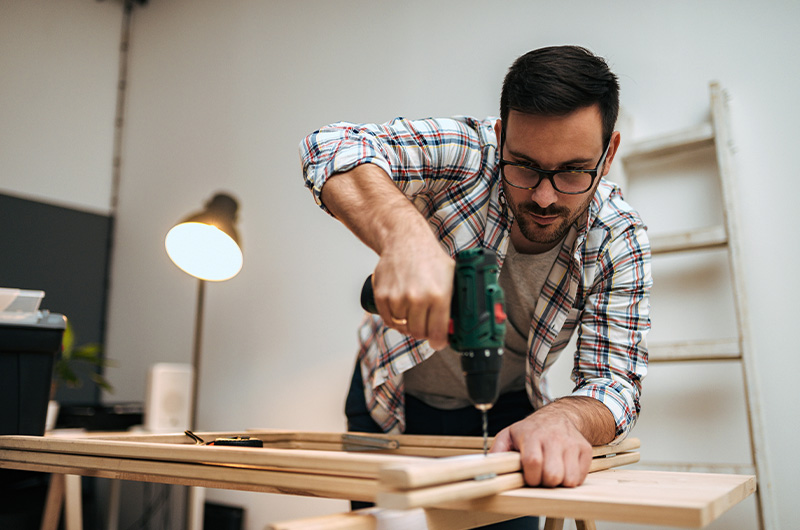 man using drill into wood